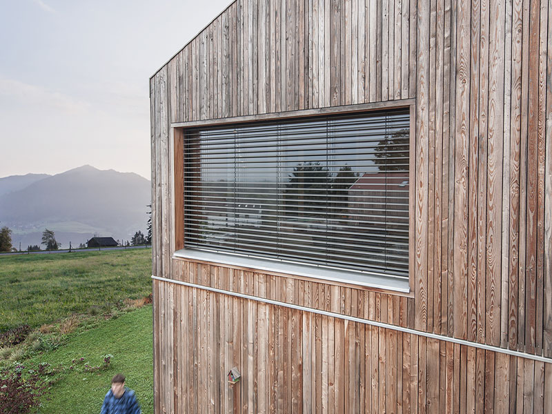 Außenjalousie an einer großflächigen Glasfront, Haus ist verkleidet mit Holz