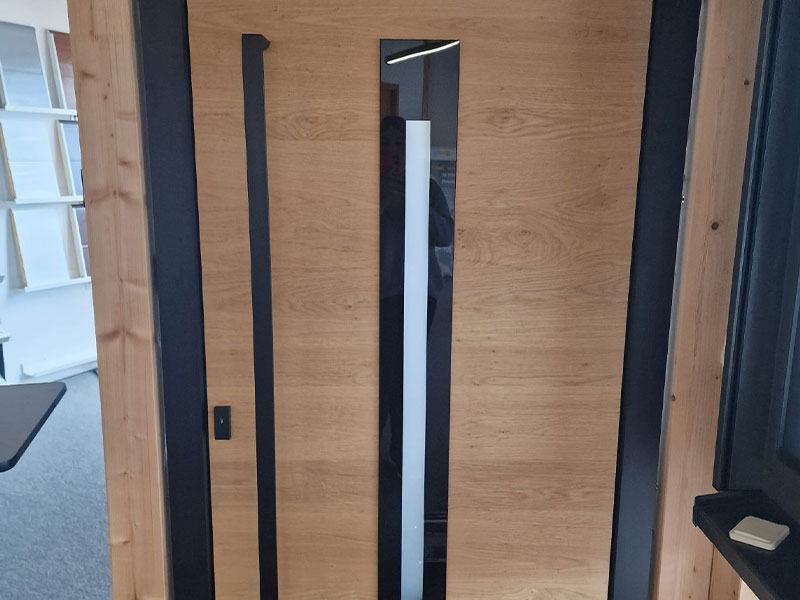 Haustür mit Eiche-Holzoptik und schwarz glänzenden Akzenten und dünnem Milchglas in der Mitte