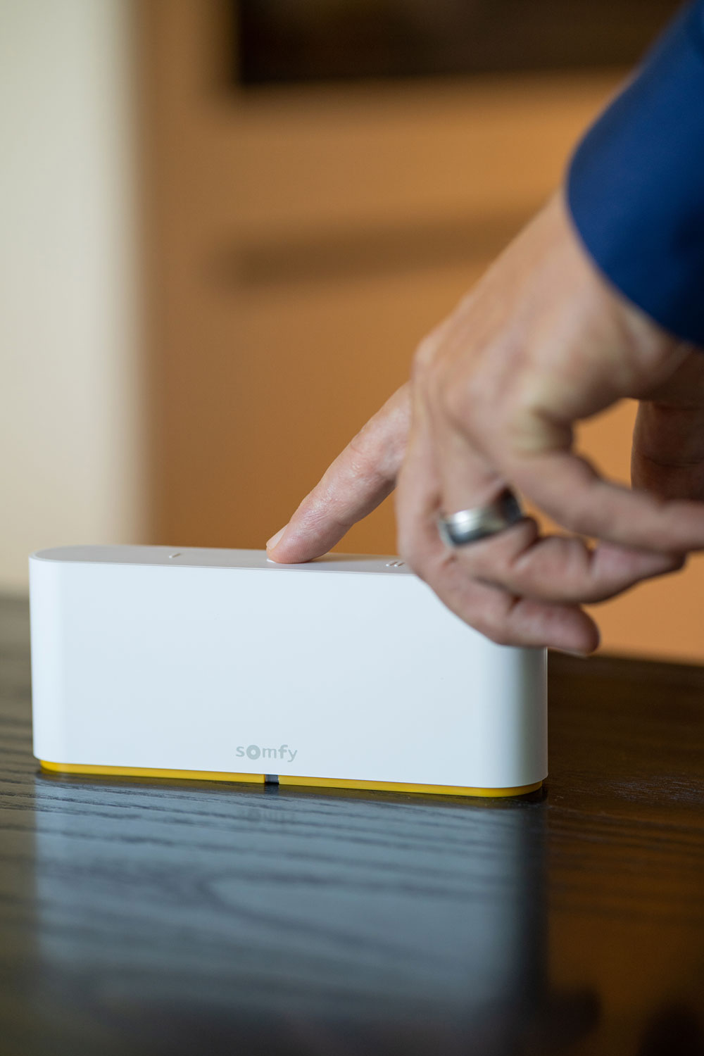 Weiße Smart Home Zentrale für das vernetzte Zuhause auf einem dunkelholzigen Tisch